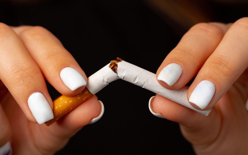 A woman holding a cigarette, raising the risk of oral cancer.