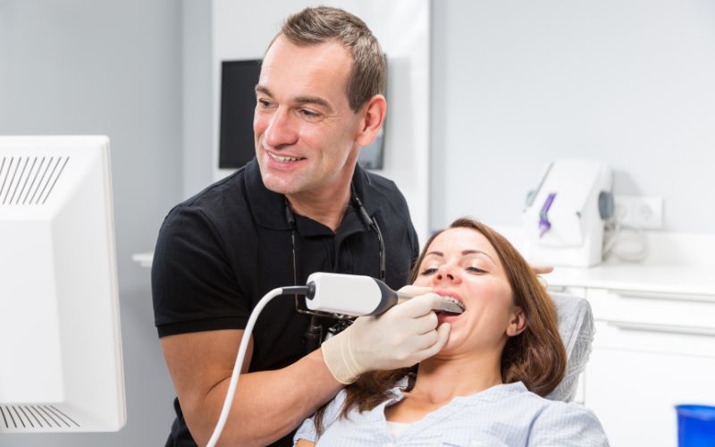 A dentist is using CEREC technology to examine a woman's teeth.