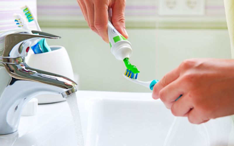 A woman is maintaining her tooth enamel by using an toothbrush.
