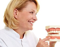 Confident Hamilton dentist pointing at model teeth for dental implant