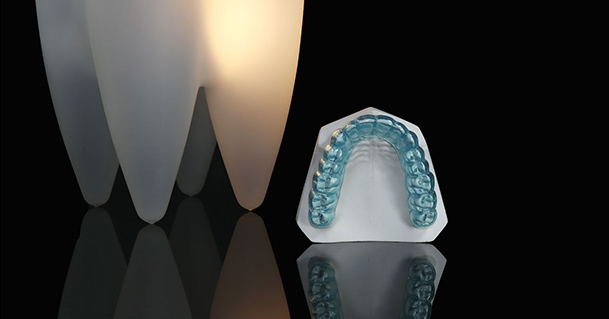 Transparent blue dental night guard next to giant model tooth at hamilton dentistry