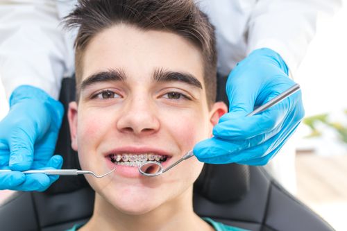 Smiling teenage boy with traditional braces undergoing dental exam at emergency dental in hamilton