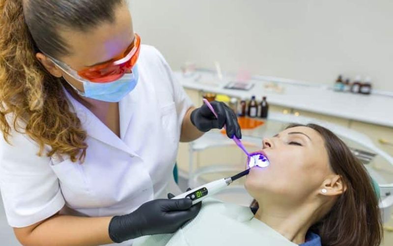 Dental hygienist cleaning sedated patient's teeth in dentist emergency hamilton