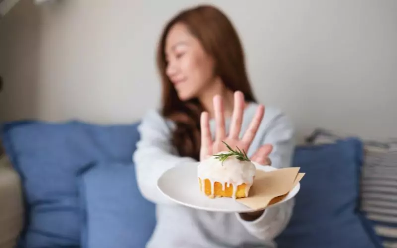 A woman displaying tooth enamel while holding a plate with a cupcake on it.