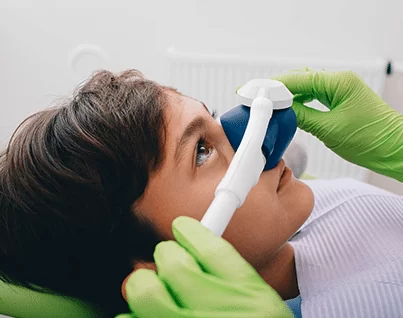 Hamilton dentist applying sedation mask to scared child's nose in sedation dentistry