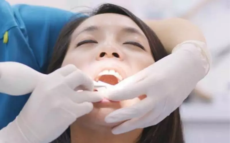 A pregnant woman is having her teeth examined by a dentist.