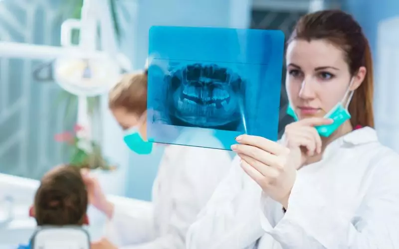 A woman is holding up an x - ray of her teeth.